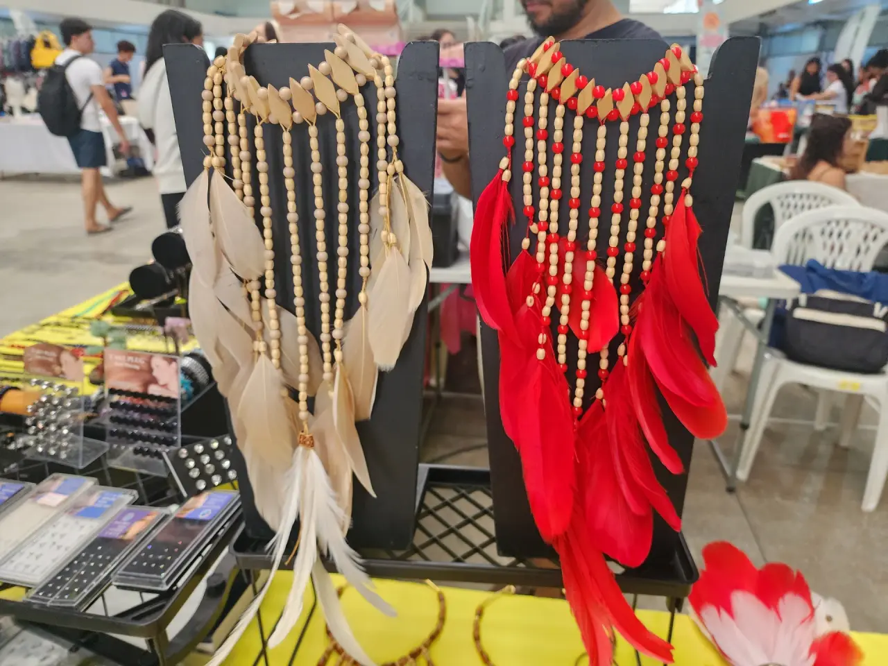 Colares com penas em tons claros e vermelhos